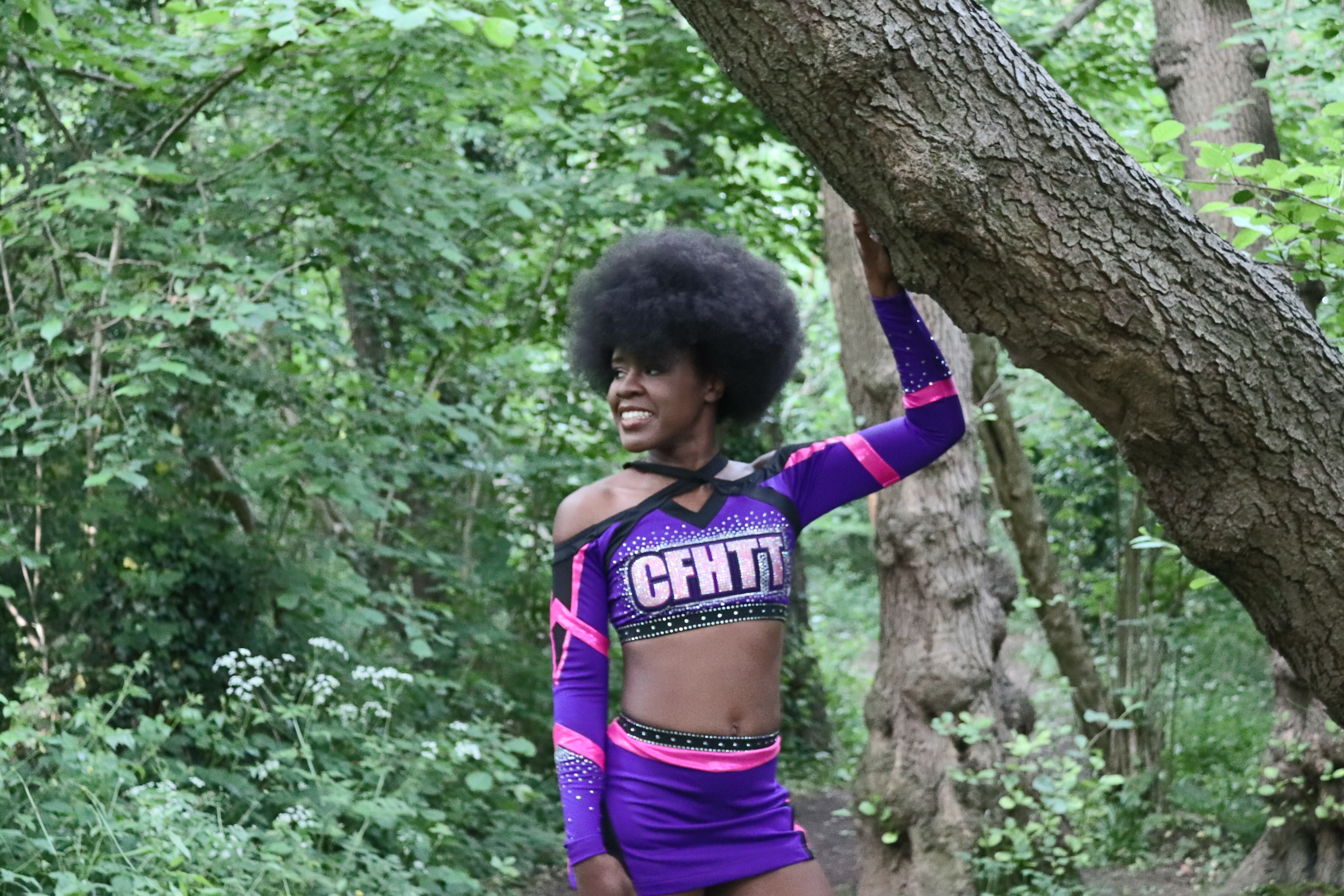 this is black female cheerleader in a purple, pink and black uniform with big afro hair